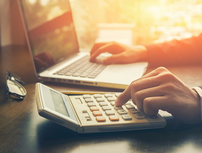 A person working on a computer and calculator representing Tax Management